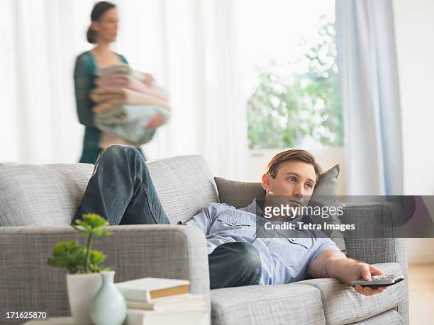 usa, new jersey, jersey city, man lying on sofa watching tv - couch potato stock pictures, royalty-free photos & images