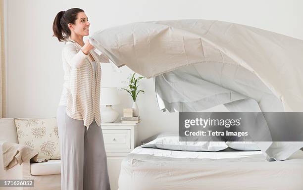 usa, new jersey, jersey city, woman spreading sheet on bed - bedding stock-fotos und bilder