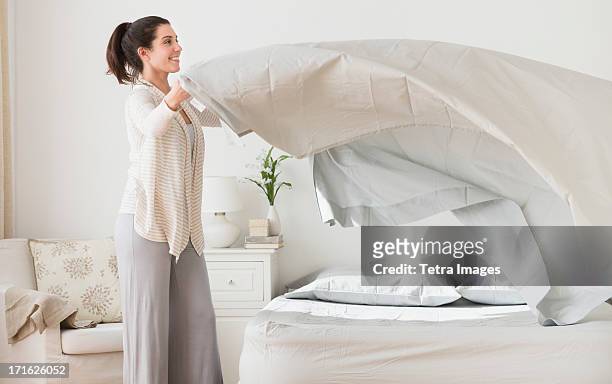usa, new jersey, jersey city, woman spreading sheet on bed - bedding foto e immagini stock
