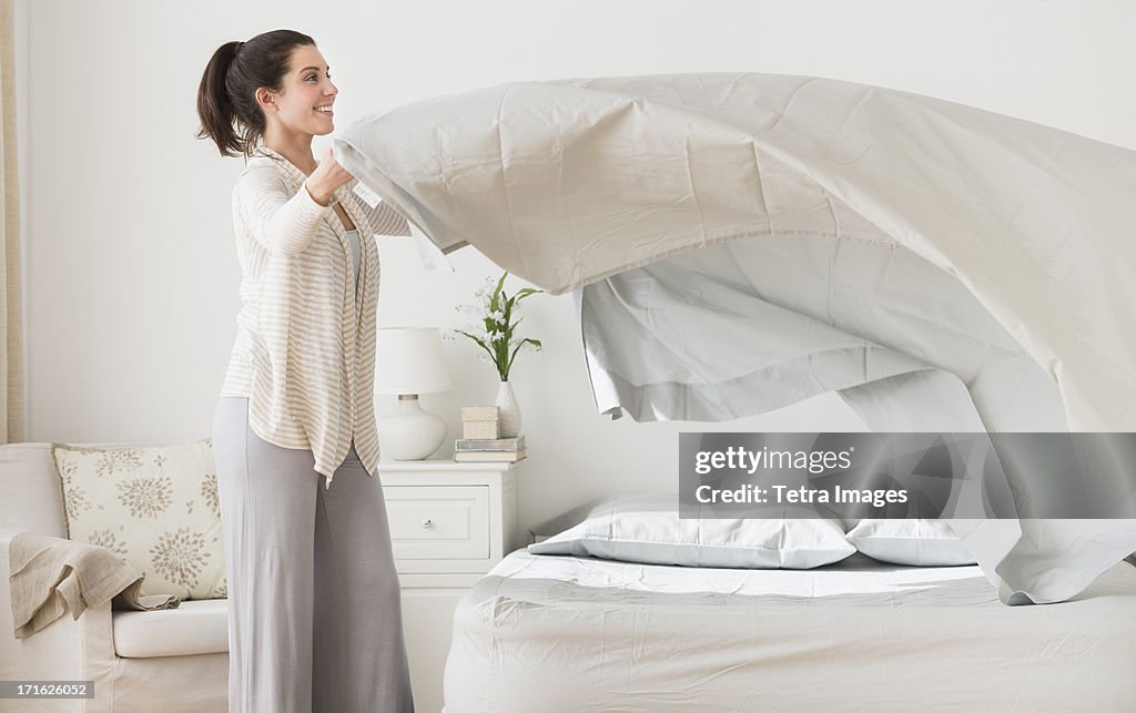 USA, New Jersey, Jersey City, Woman spreading sheet on bed