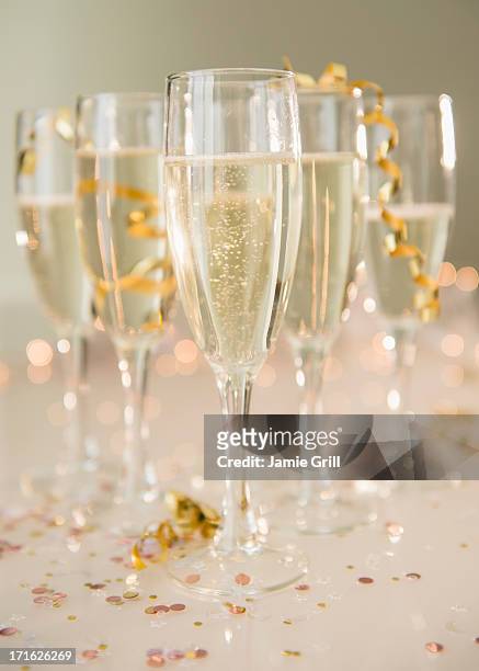 champagne flutes on table decorated with confetti and streamer - champagne or photos et images de collection