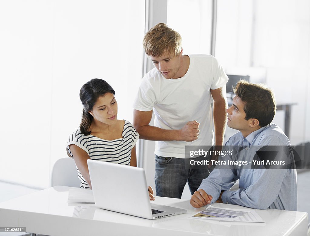 South Africa, Cape Town, Coworkers talking at table, using laptop