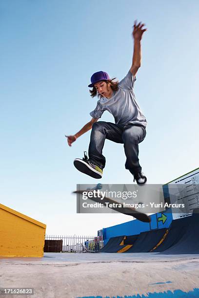 south africa, cape town, young man on skateboard jumping - man wearing cap photos et images de collection