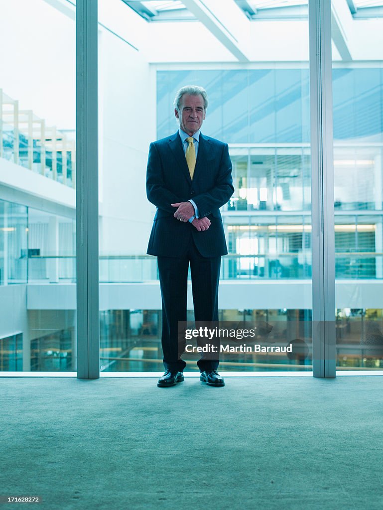 Businessman standing glass wall in office