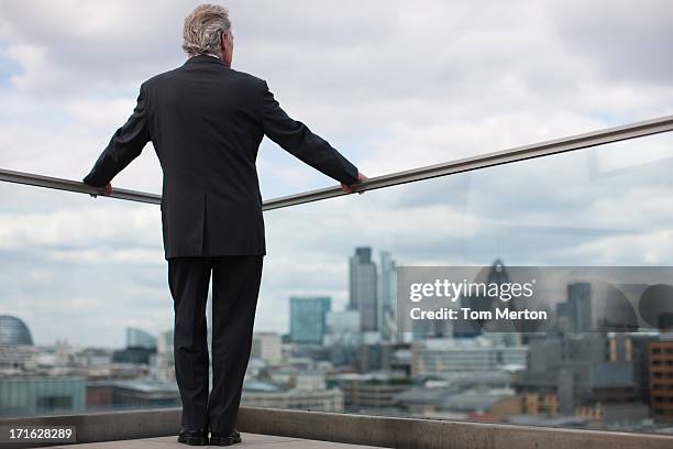 businessman standing on urban balcony - thinking man cloud stockfoto's en -beelden