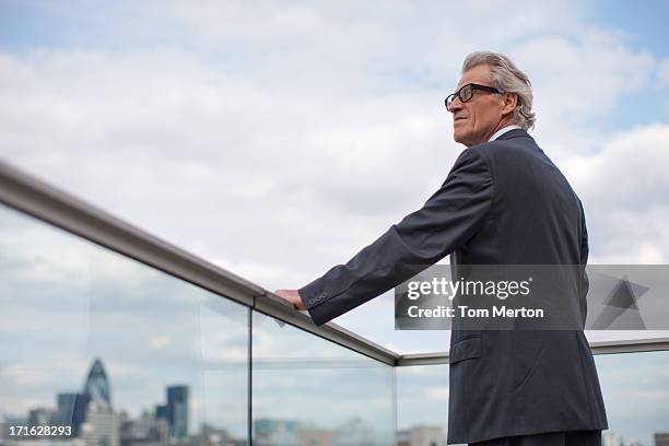 businessman standing on balcony railing - mobile phone reading low angle stock pictures, royalty-free photos & images