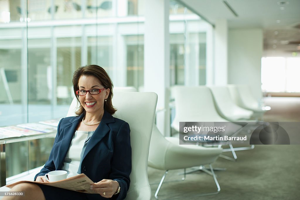 Businesswoman reading newspaper in waiting area
