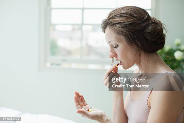woman holding pills and taking capsule - moving activity stock pictures, royalty-free photos & images