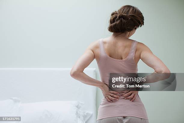woman rubbing aching back - pain stockfoto's en -beelden