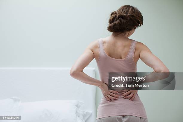 woman rubbing aching back - back pain woman stock pictures, royalty-free photos & images