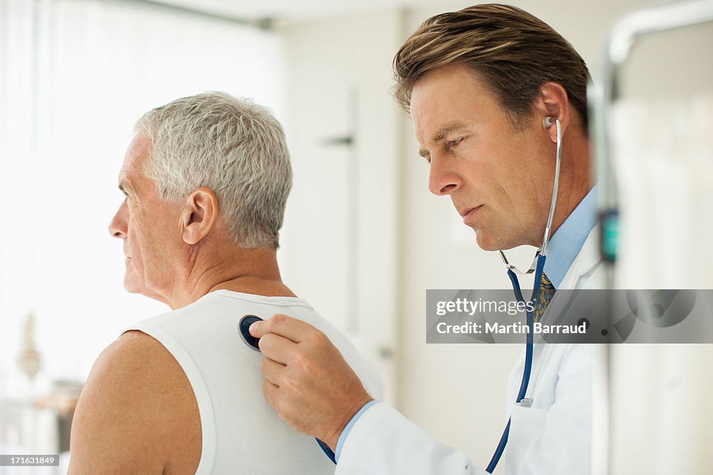 Doctor listening to mans breathing in doctors office