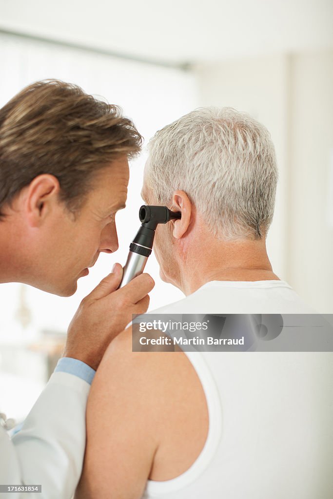 Doctor Looking In Ear Doctor Examining Patients Ear In Doctors Office High-Res Stock Photo ...