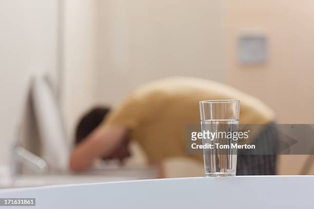 glass of dissolving medicine with vomiting man in background - hangover stock pictures, royalty-free photos & images