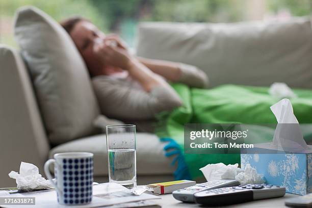 sick woman laying on sofa blowing nose - pneumonia patient stock pictures, royalty-free photos & images