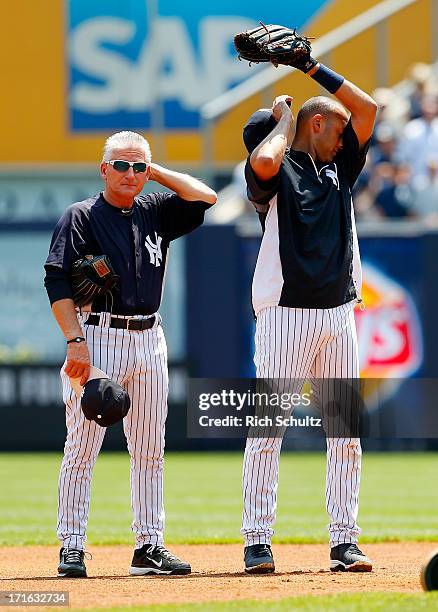 First base coach Mick Kelleher and Derek Jeter of the New York Yankees stand in the infield during batting practice before the start of their game...