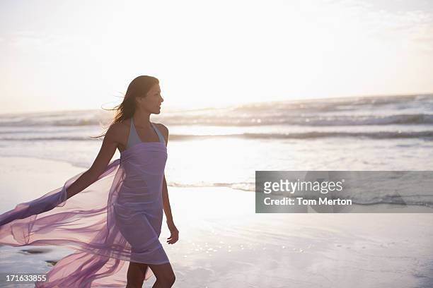 woman walking on beach - skirts blowing up 個照片及圖片檔