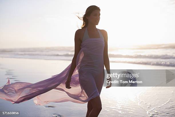 woman walking on beach - skirts blowing up 個照片及圖片檔