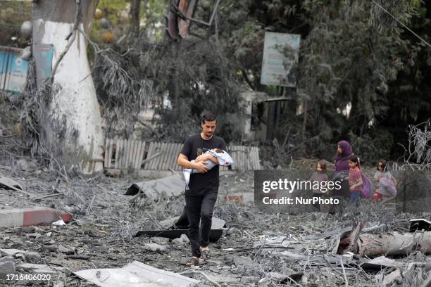 Palestinian man walks past a heavily damaged building following Israeli airstrikes on Gaza City's al-Rimal district, on October 10, 2023.