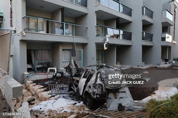 Picture taken outside a hotel in the southern Israeli city of Ashkelon shows a car destroyed in a rocket attack from the Gaza Strip on October 10,...