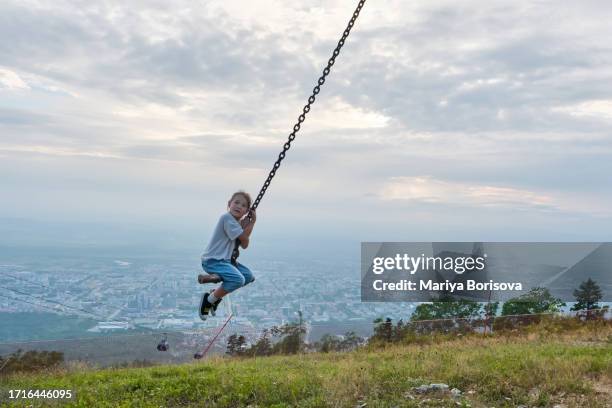 a girl swings on a chain above the city. - girl floating above city fotografías e imágenes de stock