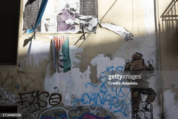 View of a street art work depicting a woman throwing a bucket of water at two Israeli soldiers on a wall in Naples, Italy on October 10, 2023.