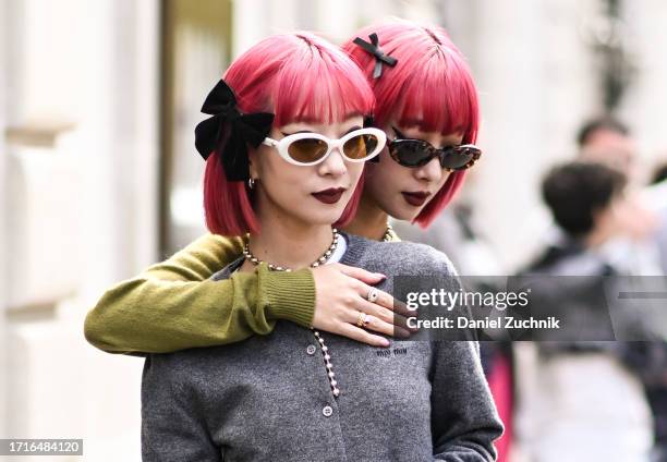 Ami Suzuki and Aya Suzuki of Amiaya are seen wearing Miu Miu gray and green cardigans, Miu Miu underwear, orange stockings and black and white shoes...