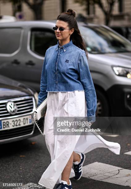 Guest is seen wearing a blue Miu Miu denim shirt, white skirt and Adidas sneakers outside the Miu Miu show during the Womenswear Spring/Summer 2024...