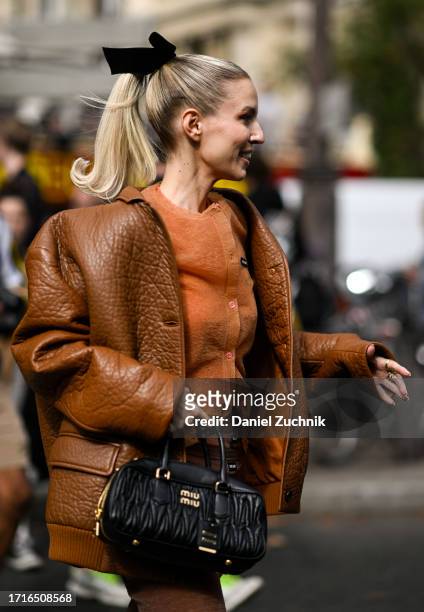 Leonie Hanne is seen wearing a Miu Miu brown coat, orange Miu Miu top and black Miu Miu bag with a hair bow outside the Miu Miu show during the...