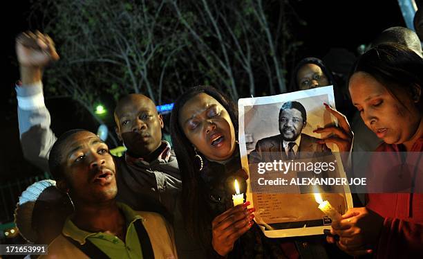 Group of well-wishers hold candles and a photo of Nelson Mandela as they pray for his recovery outside the Mediclinic heart hospital where he is...