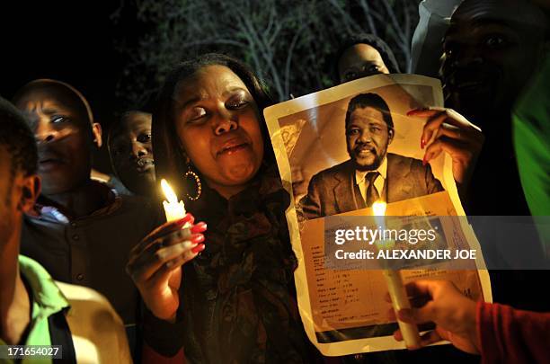 Group of well-wishers hold candles and a photo of Nelson Mandela as they pray for his recovery outside the Mediclinic heart hospital where he is...