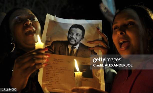 Well-wishers hold candles and a photo of Nelson Mandela as they pray for his recovery outside the Mediclinic heart hospital where he is hospitalized...