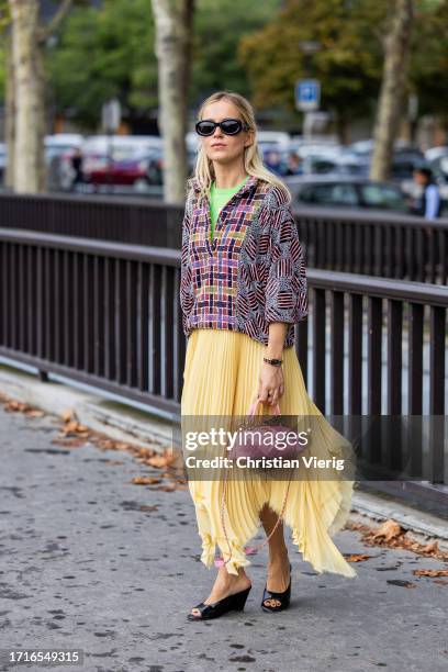 Monica Anoz wears yellow pleated skirt, pink bag, mixed pattern jacket outside Chanel during the Womenswear Spring/Summer 2024 as part of Paris...