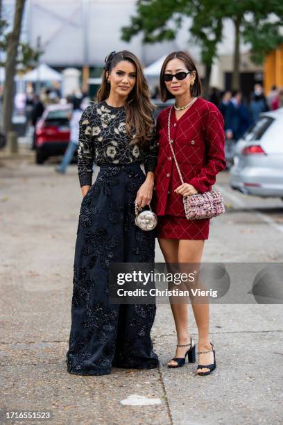 Camila Coelho wears black wide leg high waisted pants, shirt with print & Aimee Song wears red blazer, skirt, bag, black sandals, necklace,...