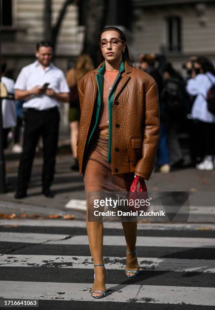 Ginevra Mavilla is seen wearing a brown Miu Miu jacket, orange sweater, sheer skirt, silver heels and red Miu Miu bag with glasses outside the Miu...