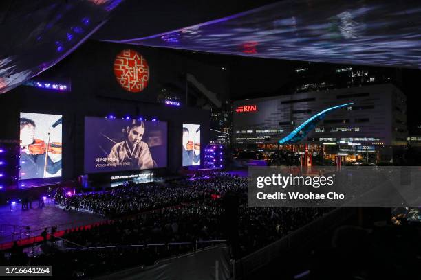 People sit in the open-air theater at Busan Cinema Center enjoying the opening ceremony of the 28th Busan International Film Festival on October 4,...