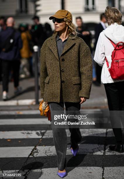 Guest is seen wearing a green coat, gray top, gray pants, purple heels, tan hat and orange bag outside the Miu Miu show during the Womenswear...