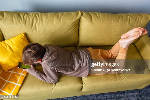 a teenage boy playing on his mobile phone while lying on his front on a sofa - sole of foot stock pictures, royalty-free photos & images