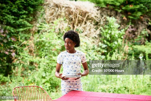 teenage girl holding plates and looking away - place setting stock pictures, royalty-free photos & images