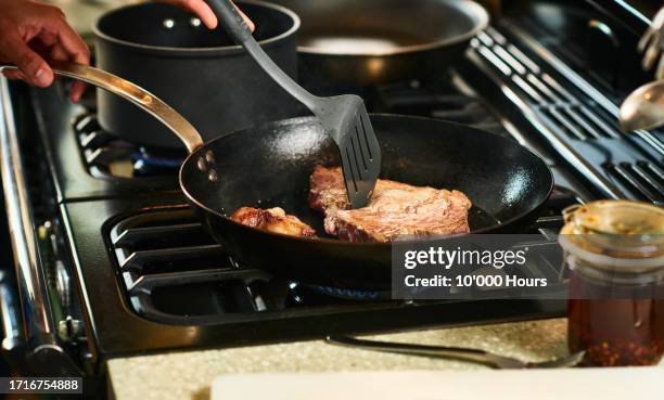 person using spatula to cook steak in frying pan - cut of meat stock pictures, royalty-free photos & images