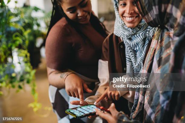 three friends are ordering some food with a delivery mobile app - north african culture stock pictures, royalty-free photos & images