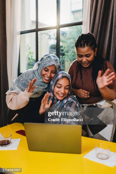 three friends are making a video call with a laptop at home - north african culture stock pictures, royalty-free photos & images