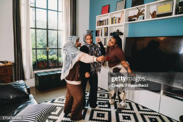 three friends are dancing together in the living room at home - north african culture stock pictures, royalty-free photos & images