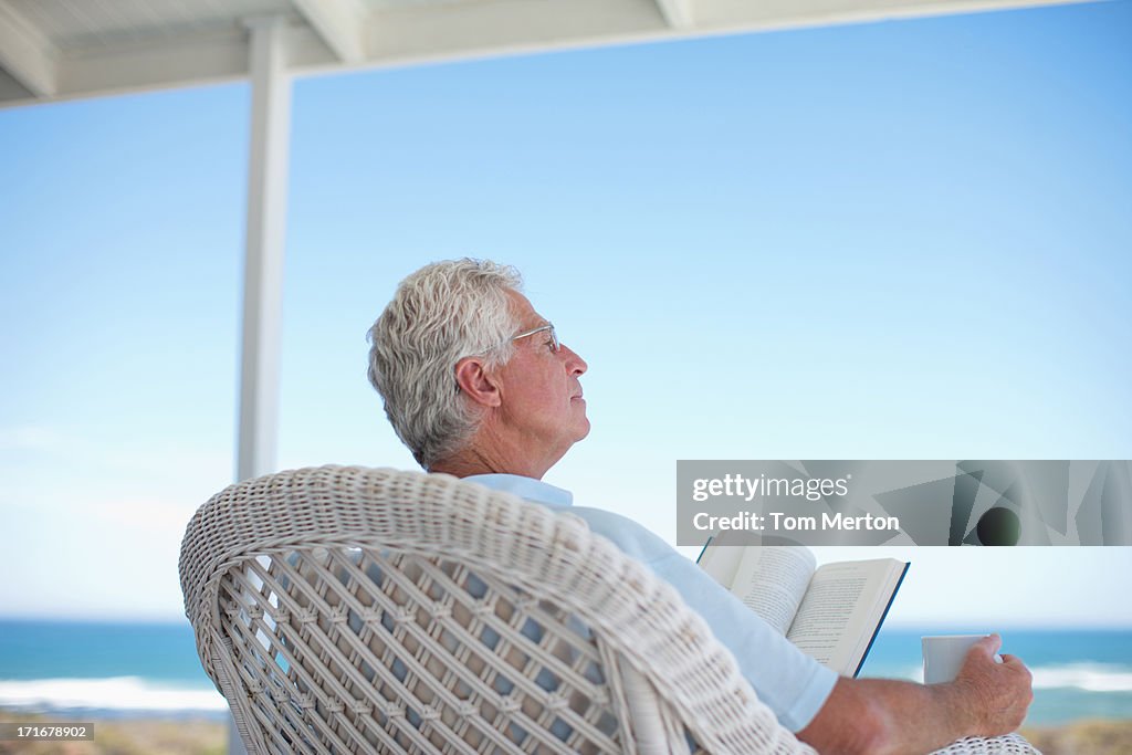 読書する老人男性ビーチのパティオ