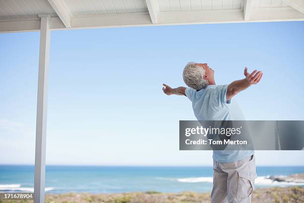 senior man standing with arms outstretched - back stretch stockfoto's en -beelden