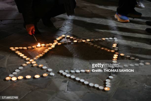 An attendee lights a candle during a gathering in solidarity with Israel after recent Hamas attacks, at the Great Synagogue of Paris, known as...