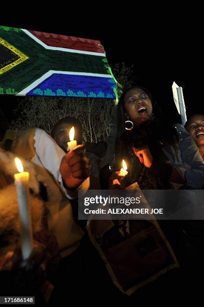 Well-wishers hold candles, a South African flag and a photo of Nelson Mandela as they pray for his recovery outside the Mediclinic heart hospital...