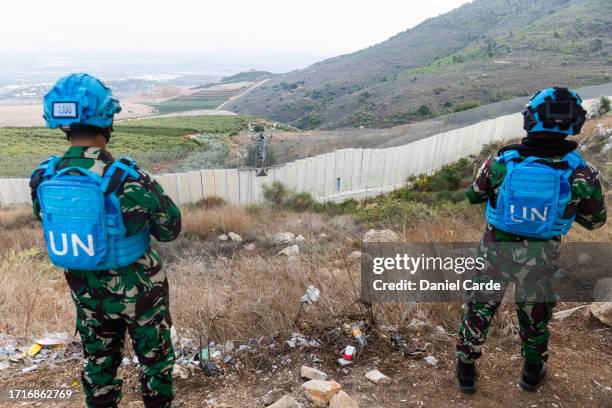 Soldiers look across the wall marking the Lebanon-Israel border along the Blue Line on October 10, 2023 in Odaisseh, Lebanon. At least three...