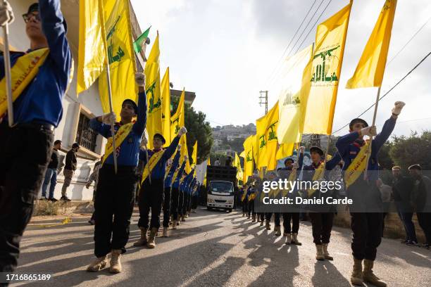 Scouts carrying Hezbollah flags while marching at a funeral for two Hezbollah soldiers who were killed yesterday by Israel Defense Forces in South...