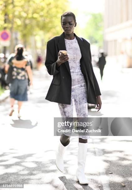 Model Achol Ayor is seen wearing a black blazer, white lace sheer bodysuit and white boots outside the Miu Miu show during the Womenswear...