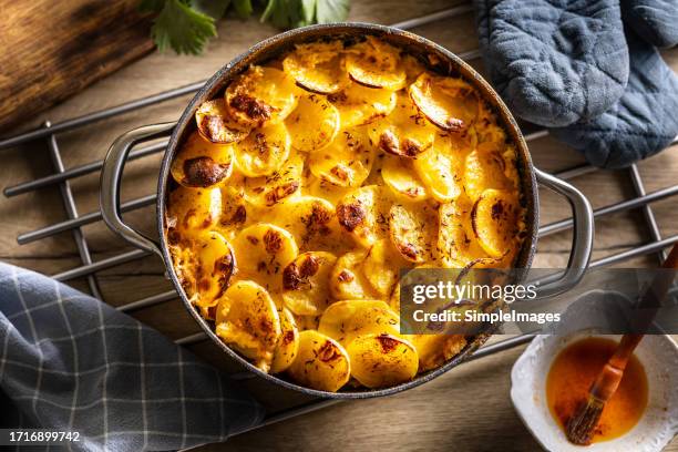 baked crispy potatoes in a ceramic pot. in eastern europe known as french potatoes. potatoes, smoked sausage, egg and cream. - aardappelgratin aardappel stockfoto's en -beelden